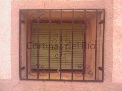 Alicantina de plástico verde detrás de la reja de una pequeña ventana