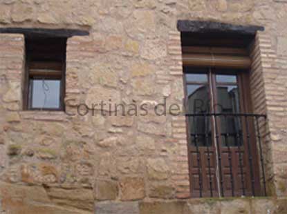 Persianas alicantinas de madera recogidas en ventana y balcón de piedra