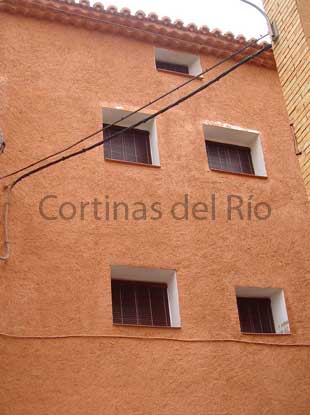 Ventanas de fachada ocre con alicantinas de madera nogal