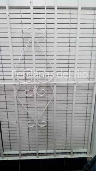 Alicantina de plástico blanca detrás de una reja del mismo color