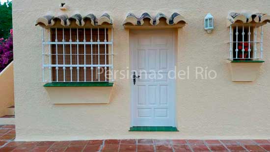 Alicantinas de plástico marrón claro detrás de las rejas de las ventanas