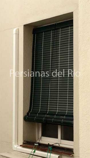 Alicantina de plástico verde botella parcialmente recogida en una ventana