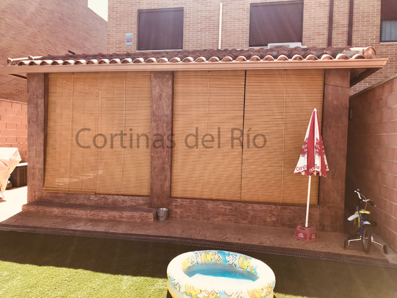 Porche con alicantinas de madera beige visto desde el jardín