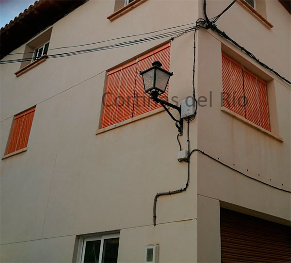 Alicantinas de plástico marrón miel en las ventanas de dos caras de una fachada