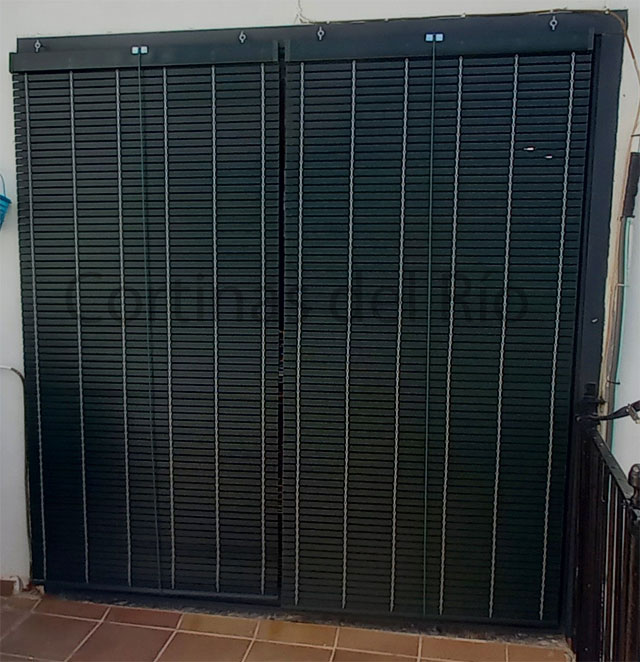 Dos alicantinas de PVC verde oscuro cubren una puerta de terraza