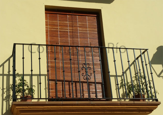 Alicantina de madera cerezo ante la puerta del balcón